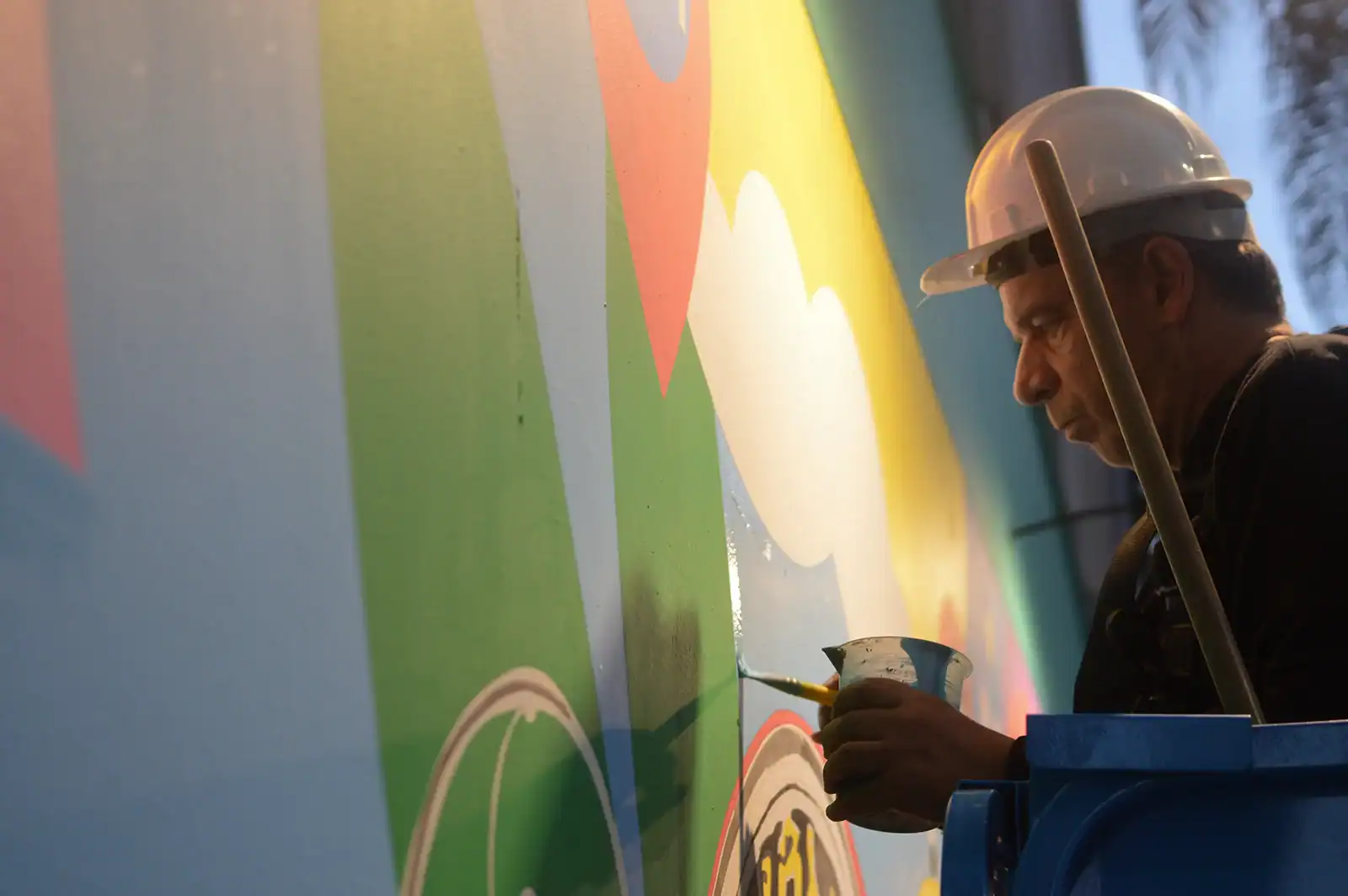 Lobo Pop Art pinta com pincel uma área colorida do mural na Rua Augusta
