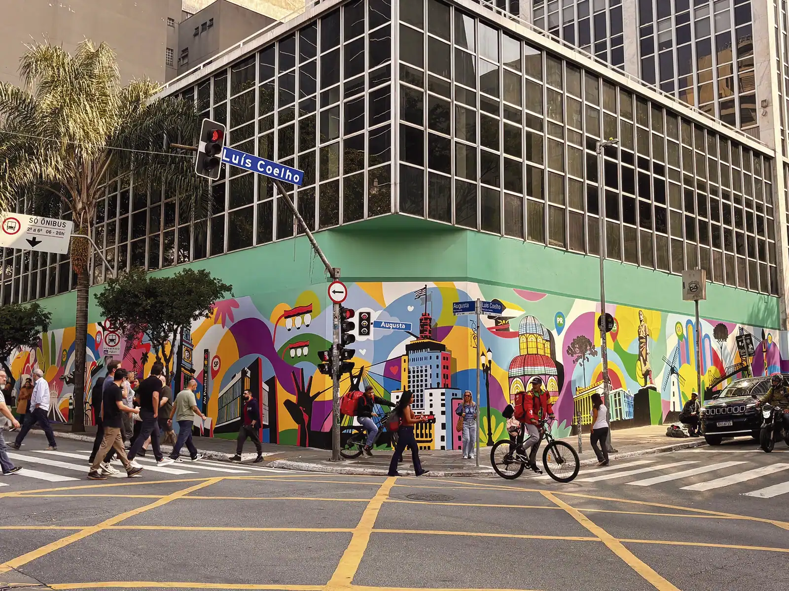 Vista das duas faces do mural Brasil em São Paulo com pedestres e ciclistas na esquina da Rua Augusta com a Rua Luís Coelho